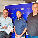 Three men with accreditation certificates