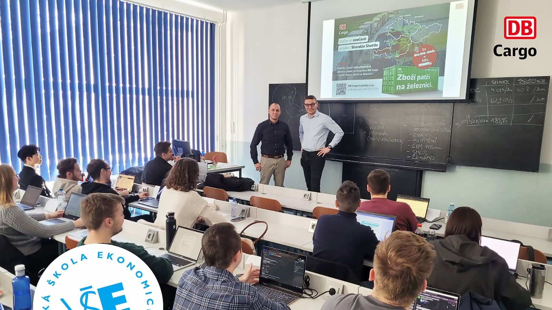 Two people of DB Cargo Czechia in front of a group of students from VSE.
