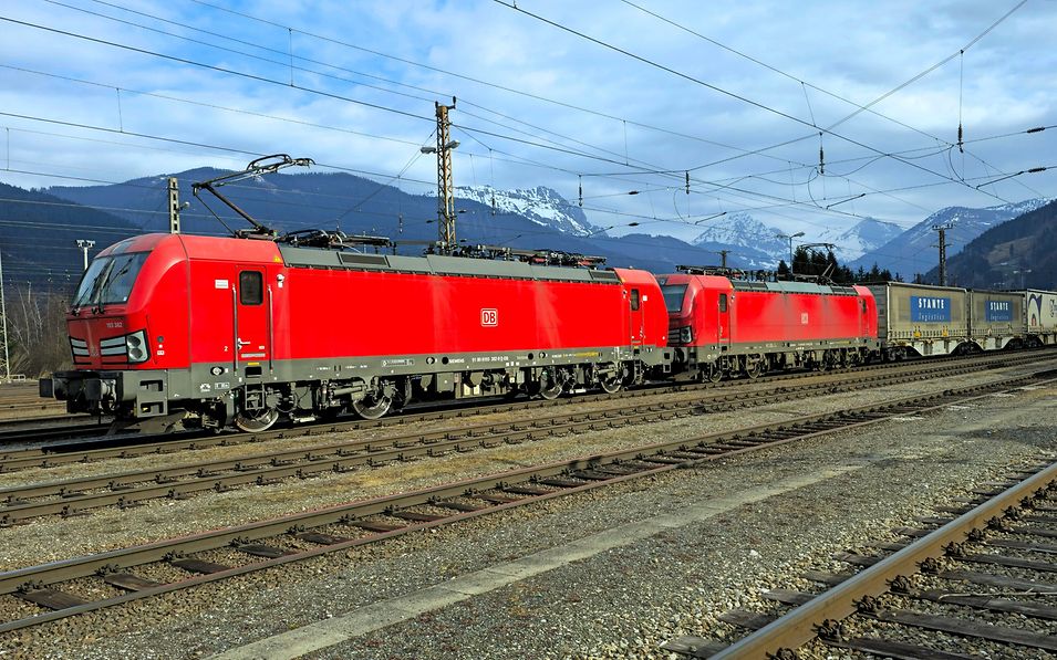 a cargo train in front of mountains